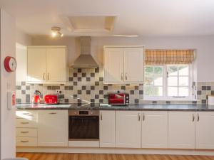 a kitchen with white cabinets and black appliances at Number Four - Ukc4966 in Tawstock
