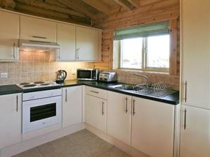 a kitchen with white cabinets and a black counter top at Partridge Lodge-W43008 in Burn