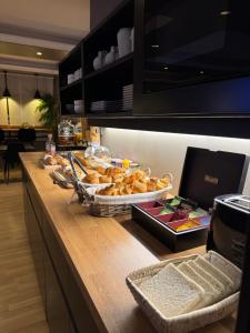 a buffet with bread and a tray of food on a counter at Cit'Hôtel l'Europe - Cholet Gare in Cholet
