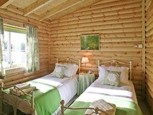a bedroom with two beds in a log cabin at Partridge Lodge-W43008 in Burn