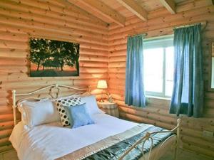 a bedroom with a bed in a log cabin at Partridge Lodge-W43008 in Burn