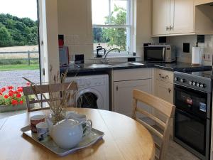 a kitchen with a wooden table and a table and chairs at Ploughmans Cottage-Uk7346 in Dyke