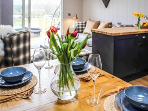 a table with a vase of flowers on a table with glasses at Buck Barn - Ukc8185 in Dolau