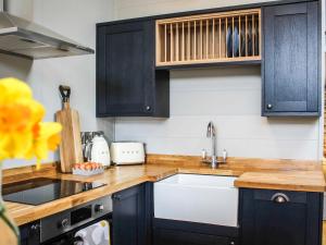 a kitchen with black cabinets and a white sink at Buck Barn - Ukc8185 in Dolau +6 photos