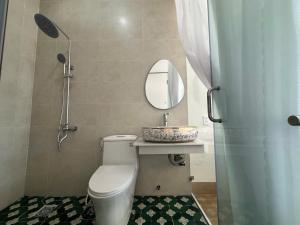 a bathroom with a toilet and a sink and a mirror at BM homestay in Buôn Dhă Prŏng