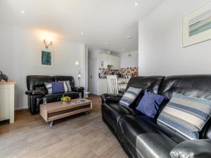 a living room with two black leather couches and a coffee table at 10 Mount Brioni in Downderry