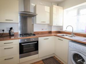 a kitchen with white cabinets and a stove top oven at Tennyson Cottage in Freshwater