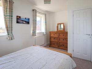 a bedroom with a bed and a dresser and a window at Tennyson Cottage in Freshwater