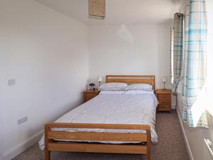 a small bedroom with a bed and two night stands at Tennyson Cottage in Freshwater