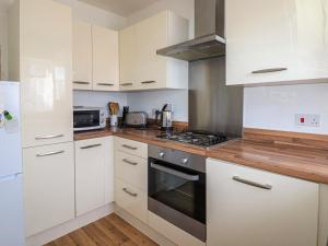 a kitchen with white cabinets and a stove top oven at Tennyson Cottage in Freshwater