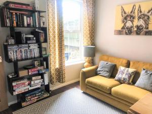 a living room with a couch and a book shelf at Kenmare Cottage in Shanklin