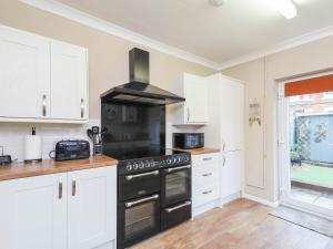 a kitchen with white cabinets and a black stove top oven at Kenmare Cottage in Shanklin