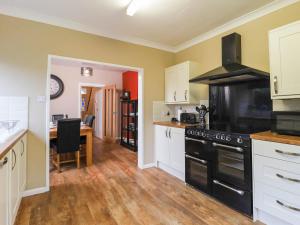 a kitchen with a black stove top oven next to a table at Kenmare Cottage in Shanklin