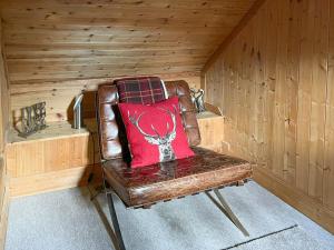 a brown leather chair with a red pillow on it at Culrain Cottage in Fort Augustus