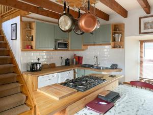 a kitchen with green cabinets and a stove top oven at Culrain Cottage in Fort Augustus