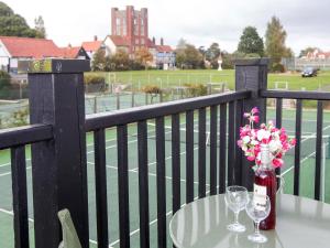 a table with two wine glasses and flowers on a balcony at 1 Bell Lodge in Thorpeness