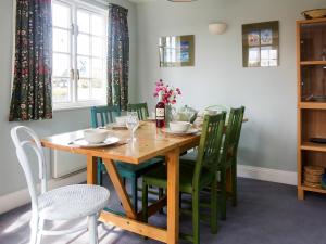 a dining room with a wooden table and green chairs at 1 Bell Lodge in Thorpeness