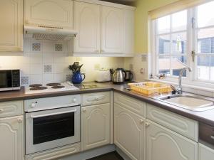 a kitchen with white cabinets and a sink at 1 Bell Lodge in Thorpeness