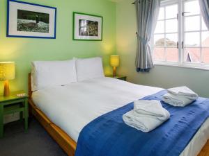 a bedroom with a large bed with towels on it at 1 Bell Lodge in Thorpeness