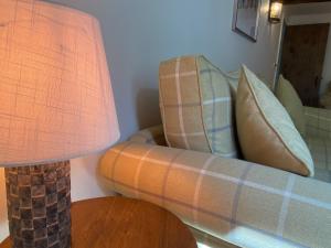 a living room with a couch and a table with a lamp at Victory Cottage in Cottesmore
