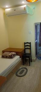 a bedroom with a bed and a chair and a fan at Mukherjee Lodge in Rāmpur Hāt +8 photos