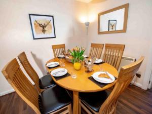 a dining room table with chairs and a wooden table with food on it at The Osprey-Ukc5062 in Aviemore