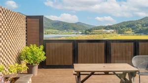 a wooden deck with a table and a view of a river at Buan Cordelia Pool Villa Pension in Buan +1 photo