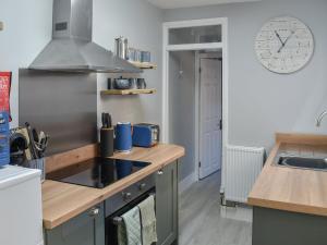 a kitchen with a stove and a clock on the wall at Curlew Cottage- Ukc5450 in Pakefield +14 photos