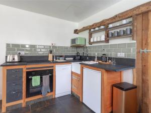 a large kitchen with white appliances and wooden cabinets at The Den - Ukc4937 in West Anstey