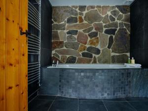 a bathroom with a tub and a stone wall at The Den - Ukc4937 in West Anstey