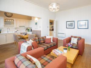a living room with couches and a table and a kitchen at The Golf Place in St. Andrews