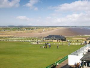 a group of people standing on a field next to a beach at The Golf Place in St. Andrews
