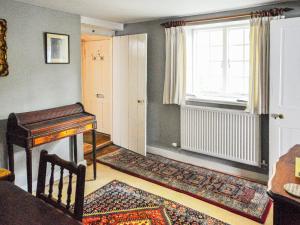 a living room with a piano and a window at Grove Cottage in Yarmouth