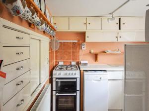 a small kitchen with a stove and white cabinets at Grove Cottage in Yarmouth