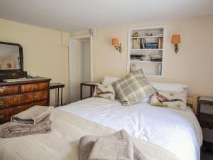 a bedroom with a bed with a dresser and a mirror at Grove Cottage in Yarmouth