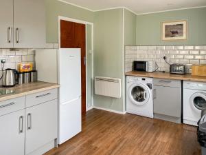 a kitchen with a washing machine and a washer and dryer at Crianlarich Cottage in Fort Augustus