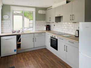 a white kitchen with white cabinets and a window at Crianlarich Cottage in Fort Augustus