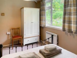 a bedroom with a bed and a cabinet and a chair at Crianlarich Cottage in Fort Augustus +5 photos