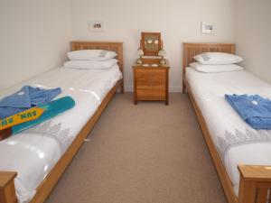 two twin beds in a room with a clock on a table at The Sanctuary in Sandown +5 photos