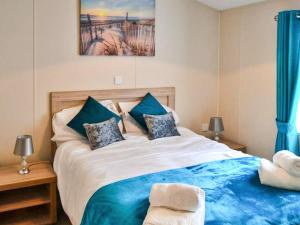 a bedroom with a large bed with blue pillows at Bluebell Lodge - Ukc5526 in West Thirston