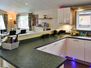 a kitchen with white cabinets and a black counter top at Bluebell Lodge - Ukc5526 in West Thirston