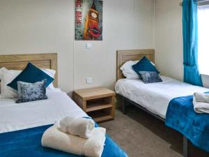 a bedroom with two beds with blue pillows at Bluebell Lodge - Ukc5526 in West Thirston +3 photos