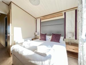 a bedroom with a large white bed with purple pillows at Knightsbridge 30 in Cameron