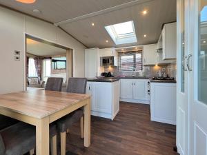 a kitchen with white cabinets and a wooden table at Knightsbridge 30 in Cameron