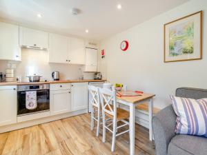 a kitchen with white cabinets and a table and a couch at White Cottage - Ukc6133 in Eastdean