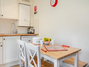 a kitchen with a wooden table and white cabinets at White Cottage - Ukc6133 in Eastdean
