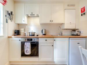 a small kitchen with white cabinets and a stove at White Cottage - Ukc6133 in Eastdean +11 photos