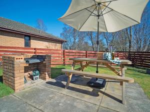 a picnic table with an umbrella and a grill at Cairngorm View - Ukc5052 in Aviemore