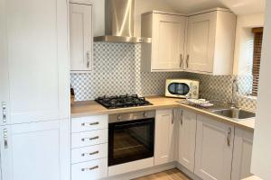 a kitchen with white cabinets and a stove top oven at Towan Cottage - Cwc79064 in Perranporth
