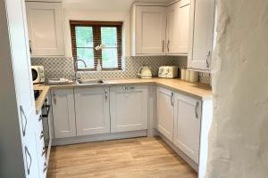 a kitchen with white cabinets and a wooden floor at Towan Cottage - Cwc79064 in Perranporth
